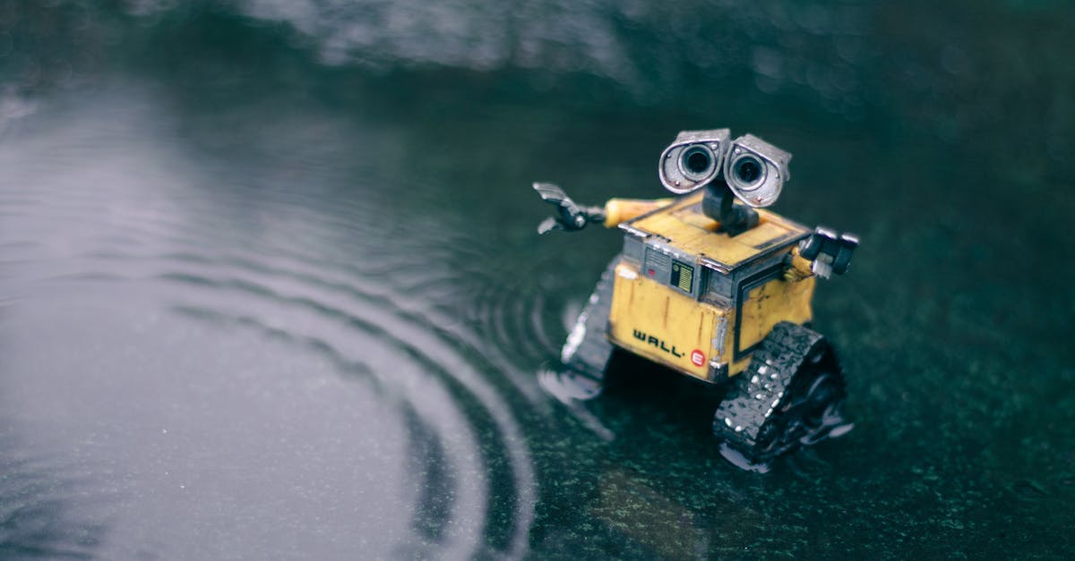 A small toy robot stands on a wet puddle, creating ripples.